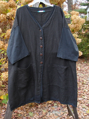 Barclay Cotton Sleeve Pocket Cardigan Unpainted Black Size 2 displayed on a clothes rack, featuring wooden buttons, curved hemline, V-neckline, drop shoulders, batiste accents, curly sleeves, and squared pockets.