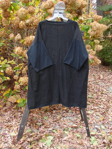 Barclay Cotton Sleeve Pocket Cardigan Unpainted Black Size 2 on display rack, showcasing wooden buttons, upward curved hemline, deep V-neck, drop shoulders, and square pockets.