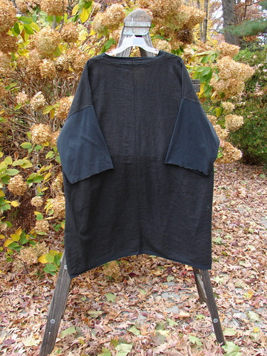 Barclay Cotton Sleeve Pocket Cardigan Unpainted Black Size 2 displayed on a swinger, featuring wooden-like buttons, curved hemline, deeper V neckline, drop shoulders, curly sleeves, and squared-off pockets.