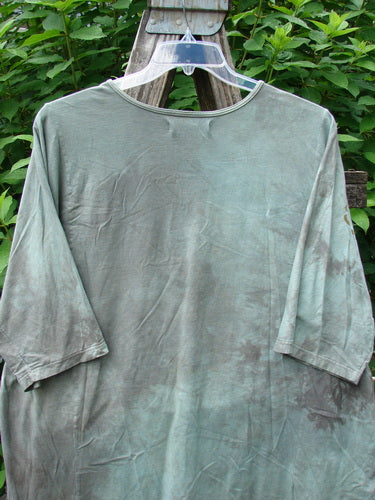 Barclay Tournesol Tunic Spotted Cat Mottled Grass Field OSFA displayed on a hanger outdoors, showcasing its tunic length, drop shoulders, loose three-quarter sleeves, rounded neckline, and varying hemline.