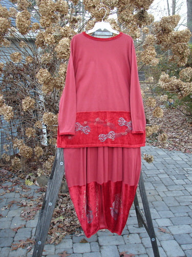 1996 Velvet Arrowhead Sofia Duo Pomegranate Size 1: A red dress on a wooden rack. Features a V neckline, velvet accents, drop waistline, and longer straight shape. Perfect for holiday or everyday wear. Bust 52, waist 52, hips 52, length 32. Bell-shaped skirt with velvet accent, kick vent, and pegged lower shape. Waist 28-38, hips 60, length 40.