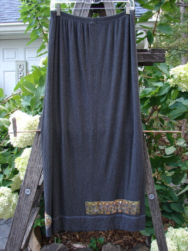 2000 Patched Rayon Lycra Rib Linear Skirt Charcoal Heather Size 1 draped on a wooden ladder, showcasing its full elastic waistband and slightly flared lower shape with exterior horizontal lower hem stitchery.