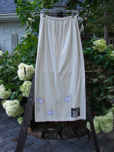 1999 Straight Skirt Fish School Dust Size 0: A long, white, organic cotton skirt with a fish school design around the hem, featuring a full elastic waistband and a straight shape, hanging on a clothesline.