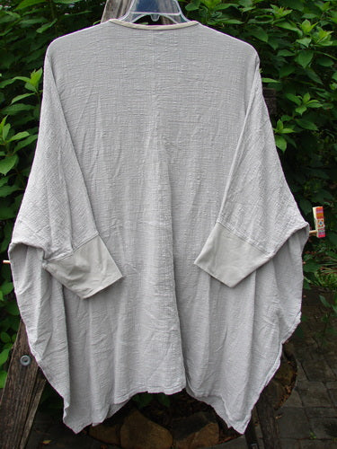 Barclay Gauze Open Front Cardigan Unpainted Natural Size 2, displayed on a rack, features generous dolman sleeves, a fully open front, tall vented sides, and contrasting lower cuffs with a flowing, boxy silhouette.