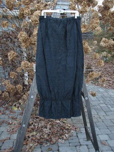 2000 Signed by Jen Shaunting Silk Gather Duo Spin Size 1; black crushed skirt on a wooden stand, showcasing a full elastic waistline and pegged uptown look.