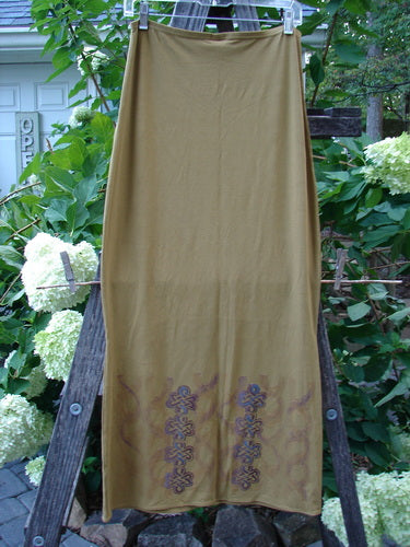 2000 NWT Rayon Lycra Narrow Skirt Celtic Celebration Bone Size 2 displayed on a clothes rack, showcasing its long, slim hourglass shape with horizontal sectional panels and a full elastic waistband.