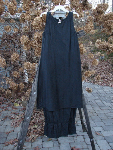 2000 Signed by Jen Shaunting Silk Gather Duo Spin Size 1: A black dress on a wooden rack, close-up of black cloth, sign, skirt, and wooden post.