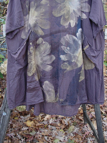 Barclay Linen Drawback Pocket Tunic Golden Daisy Plum Size 2 displayed outdoors, showcasing a lightweight, short-sleeved, purple dress adorned with floral patterns, epitomizing BlueFishFinder.com's unique vintage style.