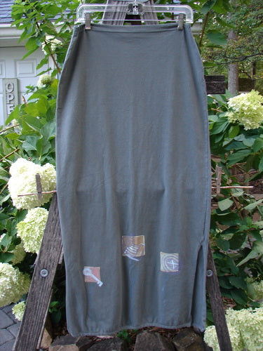 2001 Slim Skirt Junk Drawer Kelp Size 0 displayed on a wooden ladder, showcasing a flattering waistline and side vents, representing vintage Blue Fish Clothing's creativity and individuality.
