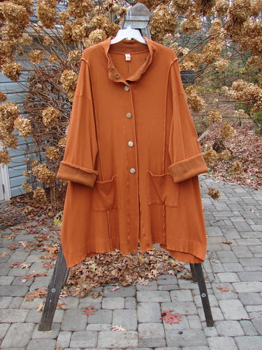 Barclay Thermal Mock Collar Coat Mixed Media Pumpkin Size 2 displayed on a swing, showing its wide sleeves, wooden buttons, and distinctive stand-up collar.