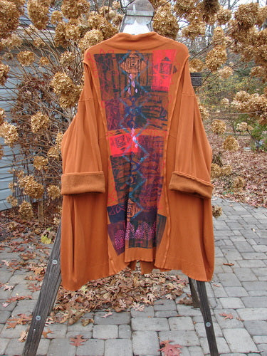 Barclay Thermal Mock Collar Coat Mixed Media Pumpkin Size 2 on a wooden stand, showcasing its long, sweeping A-line shape, wide sleeves, and detailed piping.