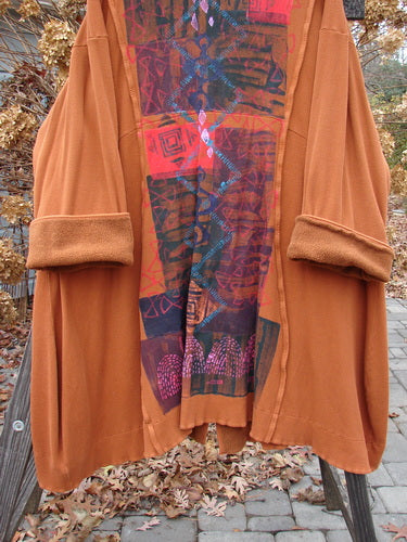 Barclay Thermal Mock Collar Coat Mixed Media Pumpkin Size 2 displayed on a hanger, showcasing its wide sleeves, exterior rolled piping, wooden buttons, and unique rear graphic arts paint.