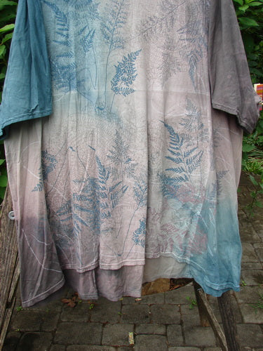 Barclay Art Tee Fern Garden Mottled Pure Dawn OSFA: Featuring a loose, three-quarter sleeve tunic with a rounded neckline and an artistic pattern, showcased on a wooden post outdoors.