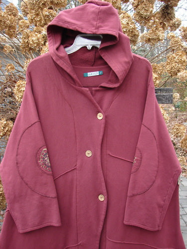 Barclay Patched Interlock Hooded Curve Coat Red Wine Size 2 displayed on a hanger, featuring a cozy hood, giant circle sleeves with patches, deep pockets, and a sweeping A-line flair.