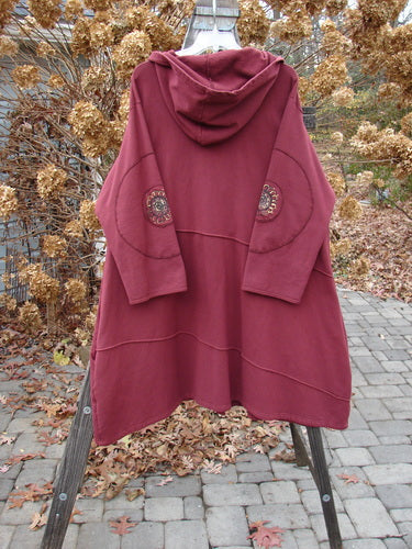 Barclay Patched Interlock Hooded Curve Coat in Red Wine Size 2 displayed on a rack, showcasing its cozy hood, giant circle sleeve patches, S-shaped button line, and deep pockets.