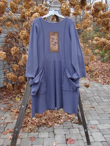 Barclay Patched Thermal Drop Pocket Dress featuring an A-line shape, exterior seams, drop shoulders, and three hand-painted patches, displayed on a wooden rack.