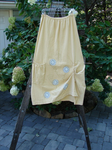 2000 Side Pocket Skirt Pinwheel Plantain Size 0, displayed on a clothes rack, featuring white buttons and a full elastic waistline, highlighting its vertical panels and unique side pocket design.