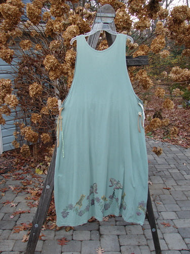 1994 Side Button Jumper Butterfly Garden River Size 1: A dress on a rack with a rounded neckline, deeper arm openings, and side buttons for an apron attachment, featuring gathered lower fabric and butterfly garden theme.