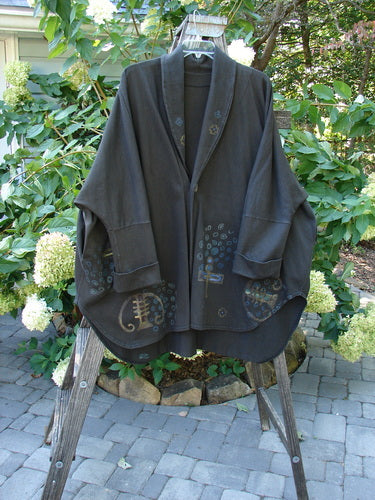 1996 Reprocessed Phoenician Jacket Abstract Travel Obsidian OSFA displayed on a rack; features oversized pockets, dolman sleeves, and a unique vintage button, showcasing Blue Fish Clothing’s creative and individualistic design.
