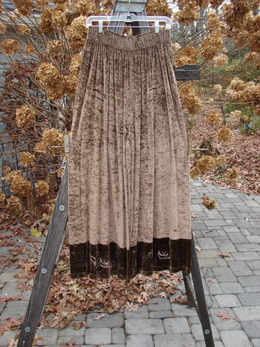 Image: A brown skirt on a wooden stand, with a close-up of a curtain in the background.

Alt text: 1997 Velvet Sanskrit Cosmos Duo Mandorla OSFA Size 2: Brown skirt on wooden stand, with curtain in the background.