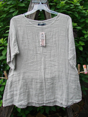 Barclay NWT Linen Springtime Top Unpainted Cloud Size 0 on a clothes rack, showcasing a rounded neckline, flowy A-line shape, and almost three-quarter sleeves, emphasizing its lightweight linen material.