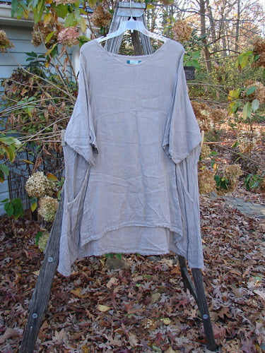 Barclay Linen Urchin Pocket Dress Unpainted Sand Size 2 displayed on a wooden rack, showcasing its lightweight, short-sleeved design, ideal for expressing individuality in vintage Blue Fish Clothing style.