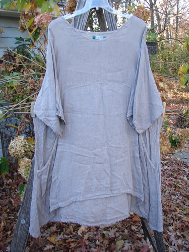 Barclay Linen Urchin Pocket Dress Unpainted Sand Size 2 hanging on a clothesline, showcasing its lightweight short sleeves and casual design, ideal for expressing individuality through vintage Blue Fish Clothing.