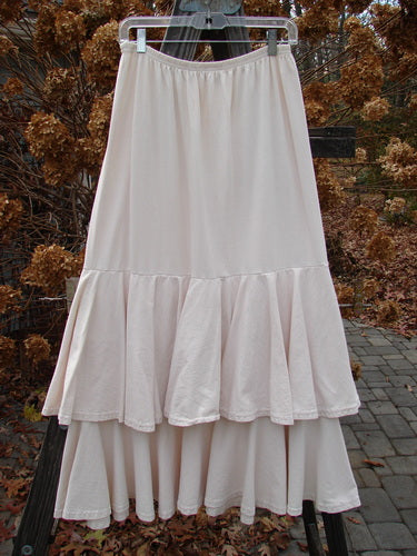 1993 Two Story Skirt on clothes rack, white dress with ruffles, black and metal objects, train track, and brick walkway.