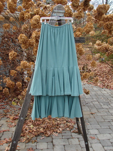 1993 Two Story Skirt Unpainted Teal Size 2 on a rack, showcasing its double-layered mid-weight cotton jersey and flouncy tiers with a full elastic waistline, emphasizing a wide, weighted lower sweep.