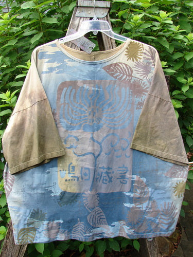 Barclay NWT Center Seam Wide Line Tee Earth & Sea Mottled Lens OSFA displayed outdoors on a hanger, showcasing its boxy shape, drop shoulders, and vertical center seam with a textured pattern.