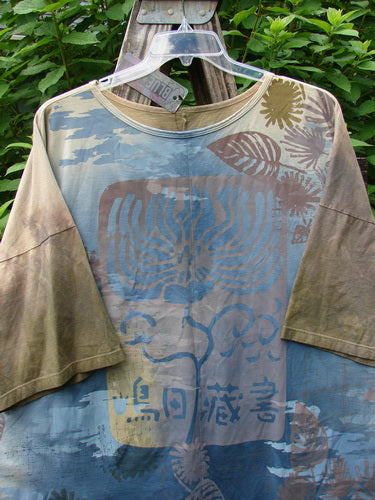 Barclay NWT Center Seam Wide Line Tee Earth & Sea Mottled Lens OSFA displayed on a swinger, highlighting its boxy shape, rounded neckline, and distinct vertical center seam in an outdoor setting.