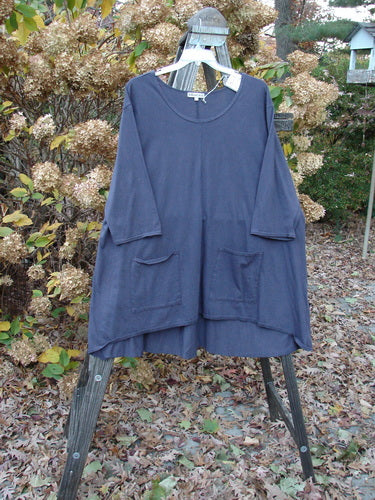 Barclay NWT Hi Low Pocket Tunic Top Unpainted Ink Size 2 displayed on a clothes rack, showcasing its soft rounded neckline, upward front scoop hemline, A-line shape, and double lower exterior front pockets.