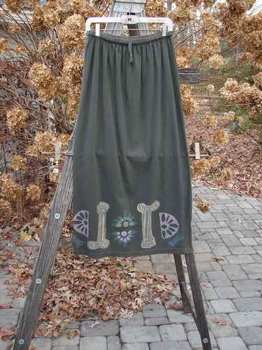 1993 Drawcord Skirt Column Black Sand Size 2 displayed draped over a wooden ladder, showcasing its full elastic waistline, slight bottom flare, and unique continuous column theme paint design.