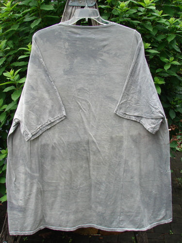 Barclay NWT Art Tee Floral Reach Raincloud Grey OSFA displayed on a hanger, showcasing its tunic length, drop shoulders, loose three-quarter sleeves, rounded neckline, and varying hemline with floral theme detailing.