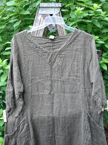 Barclay NWT Linen Cross Over Urchin Pocket Dress Unpainted Earth Size 1 displayed on a swinger, showcasing its smart cross over V neckline, drop shoulders, and distinctive double drop flop side pockets.