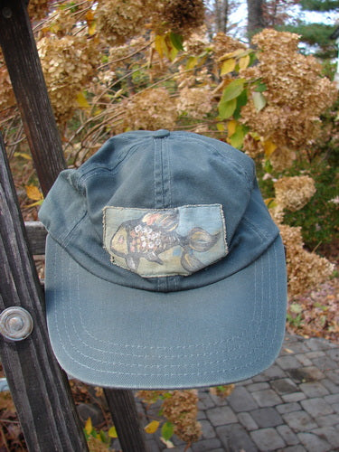 1999 Patched Men's Baseball Cap with Goldfish Blue Fish Logo, showcasing a worn look with intentional fade and stylized fish patch, adjusts via metal snap, reflecting Bluefishfinder's vintage appeal.