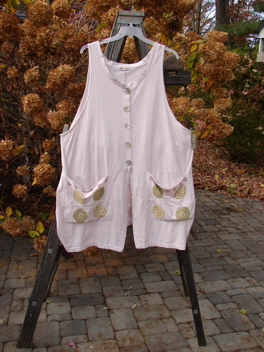 Barclay Shell Button Drop Pocket Vest in Pinwheel Pink Tile Size 2 with deep V neckline, painted front pockets, and sweeping A-line shape displayed on a clothes rack.