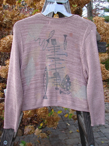 1995 Crop Cardigan Sweater featuring a Fish and Space theme in Twilight Rose Mélange, with ceramic buttons, rolled neckline, and cozy long sleeves, showcasing variegated yarn textures and stitchery.