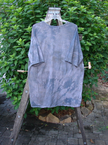 Barclay Tournesol Tunic Farm Land Mottled Grey Sky OSFA hangs freely on a clothesline, showcasing its drop shoulders, loose three-quarter sleeves, and uneven hemline, embodying Bluefishfinder.com's vintage, expressive style.