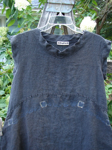 Barclay Linen Mid Layer Cap Sleeve Tunic Heart Black Size 0 displayed on a hanger outdoors, featuring a widening hemline, curved drop waist seams, and a mock mandarin collar with tiny heart patterns.