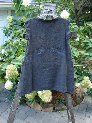 Barclay Linen Mid Layer Cap Sleeve Tunic Heart Black Size 0 displayed on a clothes rack, showcasing its unique widening hemline, downward curved empire waist seam, and mock Mandarin collar with tiny heart details.