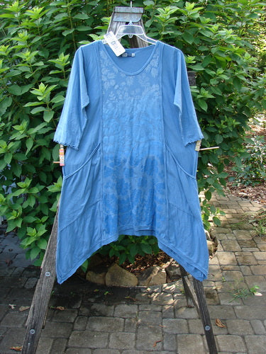 Barclay NWT Wildflower Tunic Garden Blend Blue Bird Size 0 displayed on a wooden rack, highlighting its unique dippy sides, flutter hemline, and exterior drop front pockets, embodying BlueFishFinder's creative vintage style.