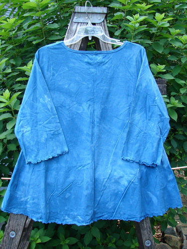 Barclay NWT Three Quarter Sleeved Cafe Tee in Shadow Blend Mottled Blue Sky, displayed on a wooden swinger, highlighting its A-line shape, rounded neckline, and curly edgings.