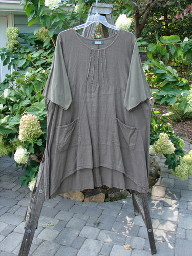 Barclay Linen Cotton Sleeve Milkmaid Dress Unpainted Mushroom Size 2 displayed on a clothes rack, showcasing its rounded neckline, sunrise pleats, empire waist seam, and diagonal front pockets.