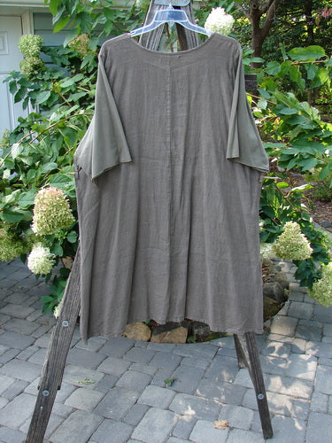 Barclay Linen Cotton Sleeve Milkmaid Dress Unpainted Mushroom Size 2 displayed on a wooden stand, showcasing its rounded neckline with sunrise pleats, empire waist seam, and diagonal front pockets.