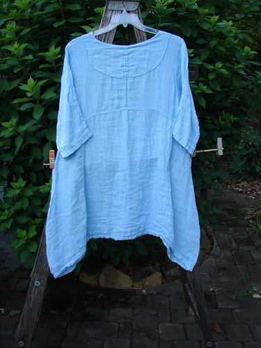 Barclay NWT Linen Cross Over Urchin Pocket Dress Unpainted Splash Size 1 on a clothesline, showcasing its cross over V neckline, drop shoulders, and double drop flop side pockets in a casual outdoor setting.