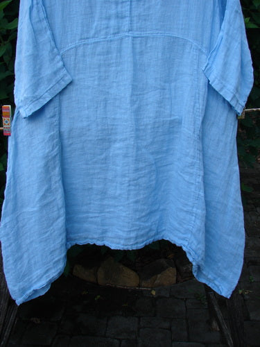 Barclay NWT Linen Cross Over Urchin Pocket Dress Unpainted Splash Size 1, featuring a V-neckline, drop shoulders, curved empire waist, and double side pockets, hanging on a clothesline.