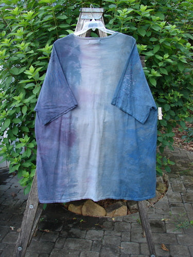 Barclay NWT Art Tee Celestial Mottled Purple Blues OSFA on a rack, showcasing its longer tunic length, drop shoulders, and loose three-quarter sleeves with a celestial-themed paint design.