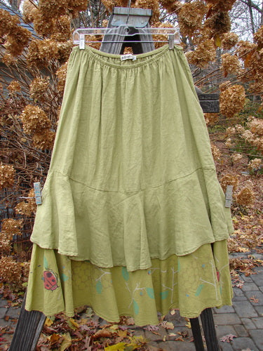 Barclay Linen Two Tier Ruffle Skirt Ladybug Yellow Olive Size 2 hanging on a clothesline, showcasing its elegant ruffles and intricate leaf pattern.