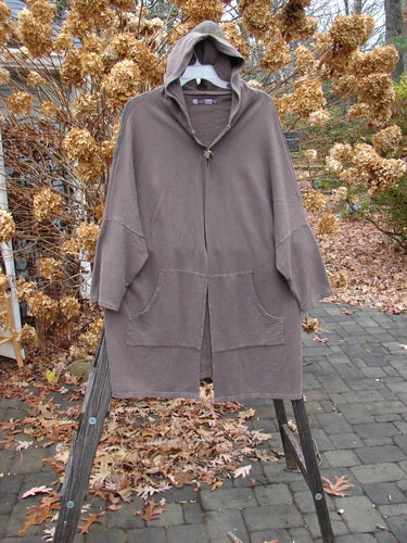Barclay Hemp Cotton Open Front Hooded Cloak Twig Stone OSFA displayed on a swing, highlighting its cozy hood, dolman sleeves, and kangaroo pockets, ideal for autumn layering.